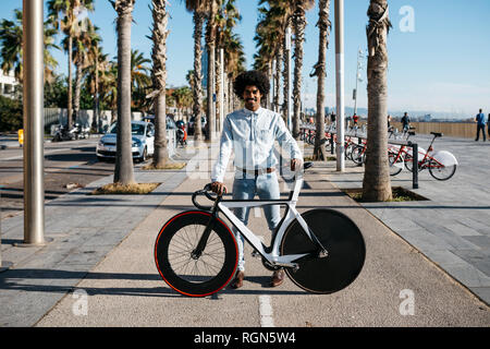 Metà uomo adulto permanente sulla strada, mostrando la sua fixie bike Foto Stock