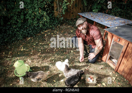 L uomo nel suo giardino, uomo alimentazione di polli ruspanti Foto Stock