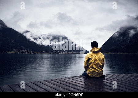 Austria, Tirolo, Lago di Achen, uomo seduto sul Boardwalk Foto Stock