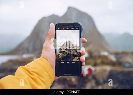 Norvegia Lofoten, Hamnoy, mano azienda smartphone per scattare la foto Foto Stock