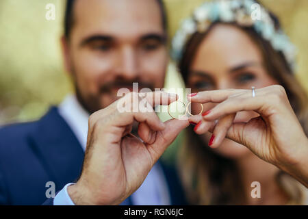 Felice coppia di sposi mostrando loro gli anelli di nozze, close-up Foto Stock