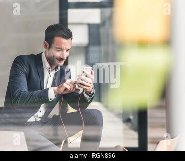 Imprenditore a parlare al telefono, utilizzare auricolari Foto Stock