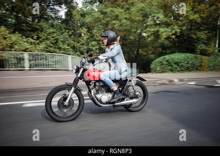 Giovane donna riding motociclo su una strada Foto Stock