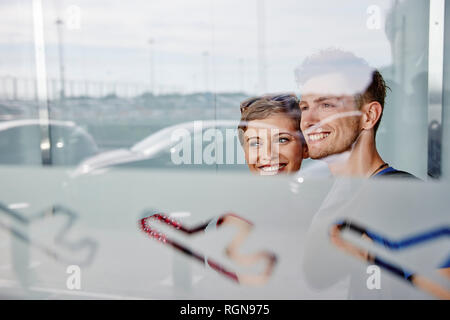 Ritratto di Coppia sorridente in aeroporto guardando fuori della finestra Foto Stock