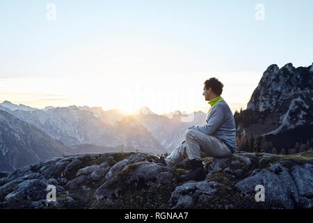 Austria, Tirolo, montagne Rofan, escursionista seduti sulle rocce al tramonto Foto Stock