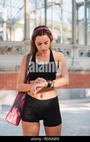 Montare la giovane donna che trasportano materassino yoga Foto Stock