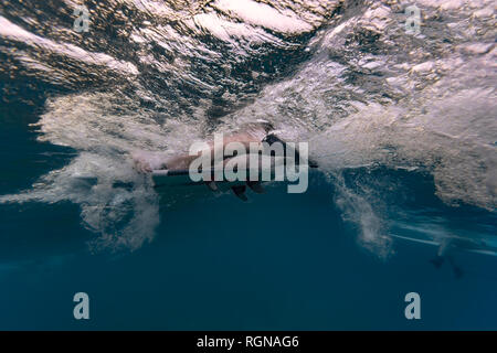 Maledives, sotto l'acqua vista di onda, surfer seduto sulla tavola da surf, ripresa subacquea Foto Stock