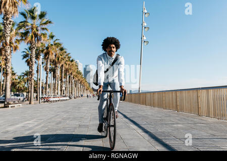 Metà uomo adulto bicykle equitazione su una spiaggia promenade, ascoltando musica Foto Stock