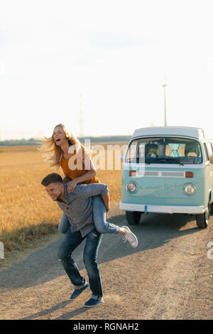 Giocoso coppia giovane a camper van nel paesaggio rurale Foto Stock