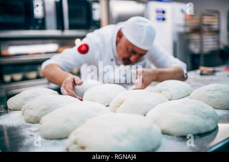 Baker lavora con impasto in forno Foto Stock