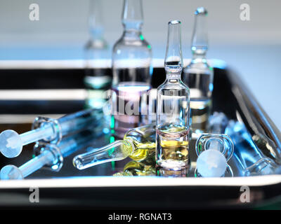Ampolle e fiale contenenti una dose del farmaco accanto alle siringhe su un vassoio chirurgico Foto Stock