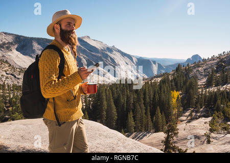 Stati Uniti d'America, in California, del Parco Nazionale Yosemite, escursionista utilizza lo smartphone e la coppa di ritegno Foto Stock