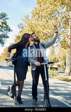 Happy business giovane con scooter prendendo un selfie Foto Stock