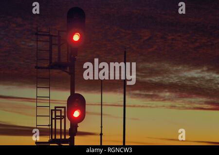 Orland Park, Illinois, Stati Uniti d'America. Un segnale rosso a proteggere un blocco dei binari della ferrovia appena dopo il tramonto. Foto Stock