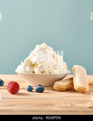 Mascarpone, biscotti savoiardi e bacche su un tavolo di legno. In casa la crema di formaggio. Foto Stock