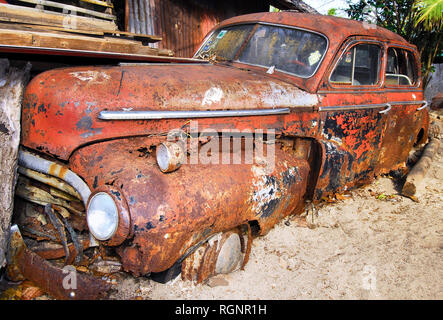 Wrack di un colore rosso, rusty Chevrolet auto del 50-esimo, intrecciato in corrispondenza di una zona spiaggia nella città di Cuyo, Cuyo Islands, Palawan Provincia, Filippine. Foto Stock