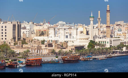 Ristorante tradizionale dhow ormeggiati in Dubai Creek, Dubai, EAU. Il vecchio quartiere mercantile della Bastikiya può essere visto in ba Foto Stock