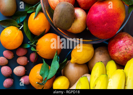 Raccolta di diversi gustosi freschi maturi frutti tropicali in ciotole e piatti sul tavolo vicino a parete Foto Stock