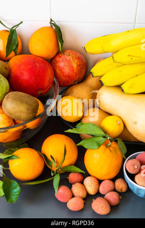 Raccolta di diversi gustosi freschi maturi frutti tropicali in ciotole e piatti sul tavolo vicino a parete Foto Stock