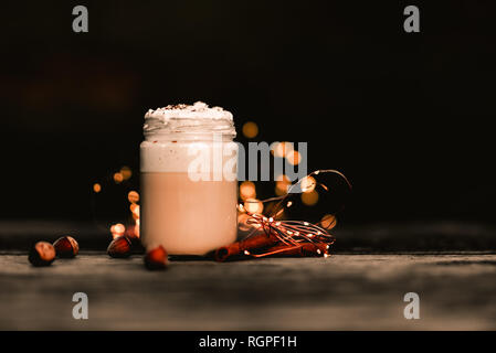 Aromatica bastoncini di cannella vicino a Giara di buonissimo caffè con panna sul legname il piano portapaziente Foto Stock