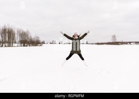 Signora giovane in inverno indossare il divertimento sulla neve prato e cielo nuvoloso di Vilnius, Lituania Foto Stock