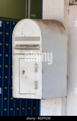 Un vicino la vista frontale di un metallo bianco sporco post box che è imbullonato alla parete al di fuori di un ufficio postale Foto Stock