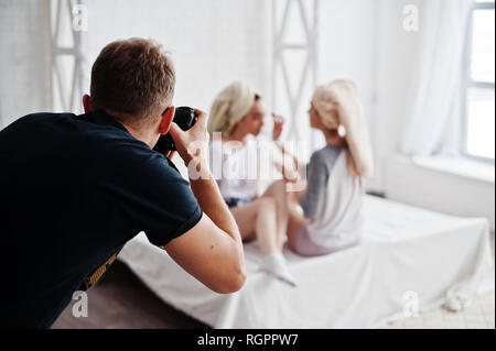 L'uomo fotografo riprese in studio due ragazze mentre fanno le proprie maschere crema. Fotografo professionista sul lavoro. Foto Stock