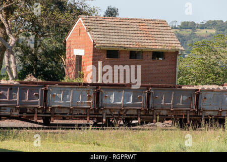 Una vista ravvicinata di un piccolo vecchio edificio abbandonato e un arrugginito carrage ferroviario che non è più utilizzato e che è arrugginita con calcestruzzo pillers Foto Stock