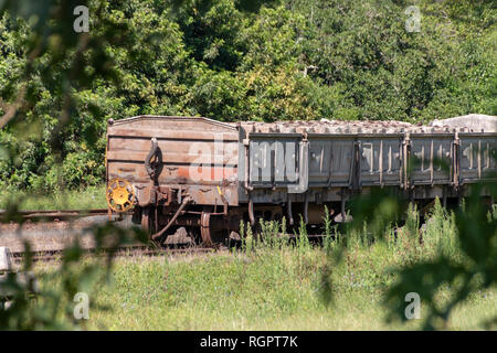 Una vista ravvicinata di un vecchio arrugginito treno aperto carrage con calcestruzzo pillers ferroviarie ancora dentro Foto Stock