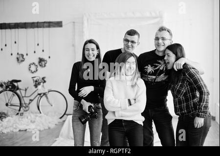 Il gruppo di cinque popoli, amici fotografi e designer sulle riprese in studio dopo la dura giornata di lavoro. Sono felice e ridere. Foto Stock