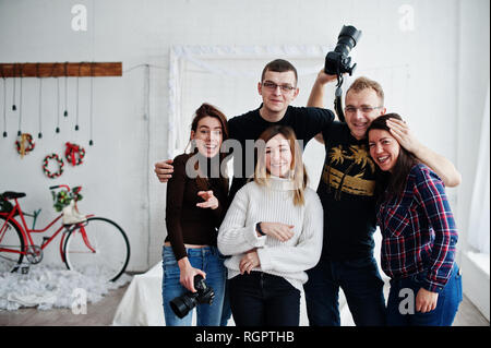 Il gruppo di cinque popoli, amici fotografi e designer sulle riprese in studio dopo la dura giornata di lavoro. Sono felice e ridere. Foto Stock