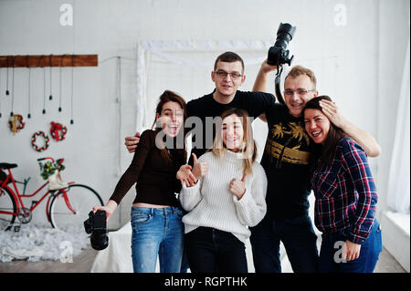 Il gruppo di cinque popoli, amici fotografi e designer sulle riprese in studio dopo la dura giornata di lavoro. Sono felice e ridere. Foto Stock