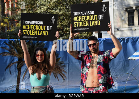 Due modelli stand su un "filo spinato" sulla spiaggia al di fuori degli uffici di TripAdvisor in Soho Square, Londra centrale, come parte di un'Amnesty International campagna chiedendo alla ditta e di altre compagnie di viaggio per arrestare elencando le camere e le attività degli insediamenti israeliani nei territori palestinesi. Foto Stock