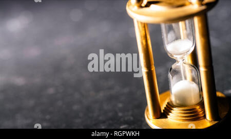 Rivoli di sabbia attraverso una clessidra, simbolizzanti timekeeping. Foto Stock