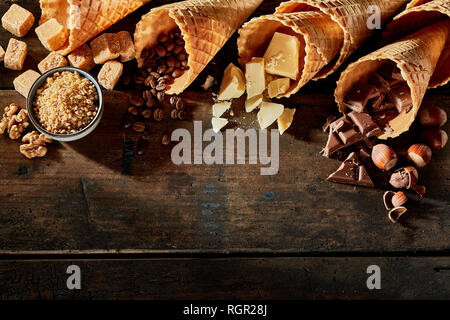 Coni riempita di cioccolato, caramello, caffè contro lo sfondo di legno Foto Stock