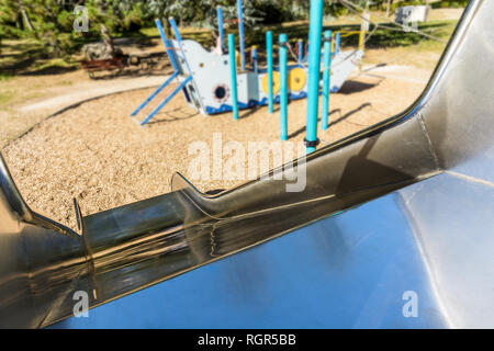 Prima Persona vista dalla cima di un acciaio inossidabile parco giochi diapositiva in un area gioco per bambini con una imbarcazione pirata in background. Foto Stock