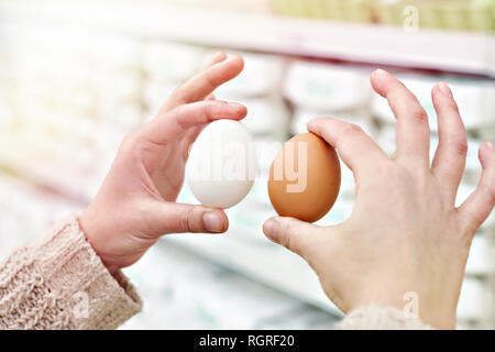 Le mani di una donna con bianco e marrone di uova in negozio Foto Stock