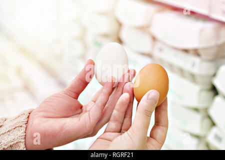Le mani di una donna con bianco e marrone di uova in negozio Foto Stock