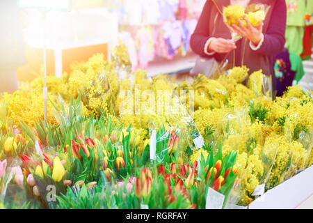 Donna compri fiori tulipani e mimosa in negozio Foto Stock