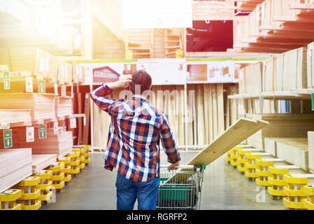 Uomo sceglie e acquista il legno compensato e pannelli in un supermercato di costruzione Foto Stock