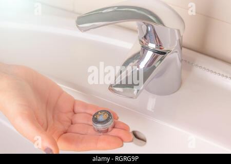 La riparazione della gru di un aeratore. La purificazione del gassatore da depositi. La mano della ragazza tiene in mano un vecchio dirty calcare aeratore del mixe Foto Stock