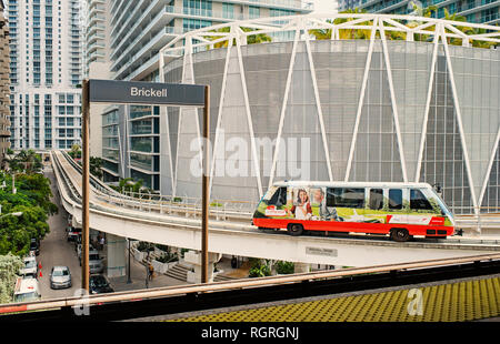 Miami, Stati Uniti d'America - 30 Ottobre 2015: il treno arriva alla stazione di brickell con il centro di grattacieli in background urbano. Metrorail o metro rail transit system sul paesaggio urbano. Metropolitan servizio di trasporto. Foto Stock