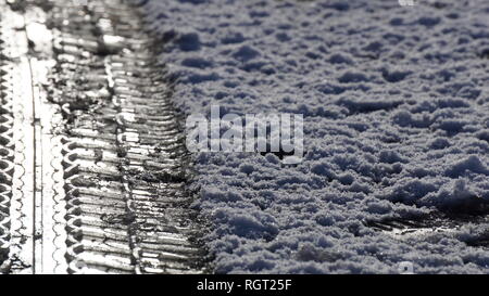 Battistrada del pneumatico segni impressi nella neve su una strada ghiacciata in inverno. Foto Stock