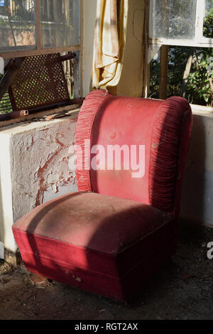 Vintage poltrona rossa ricoperta di polvere e la ragnatela. Casa abbandonata interni. Foto Stock