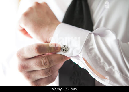 Un uomo mette su una camicia costosa con gemelli di mattina. Foto Stock