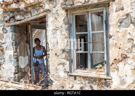 Donna in piedi nelle rovine della casa abbandonata nel villaggio greco Foto Stock