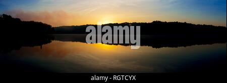 Vista panoramica del Rising Sun picchi oltre l'orizzonte di nebbia a Shelley Lake Park in Raleigh North Carolina. Foto Stock