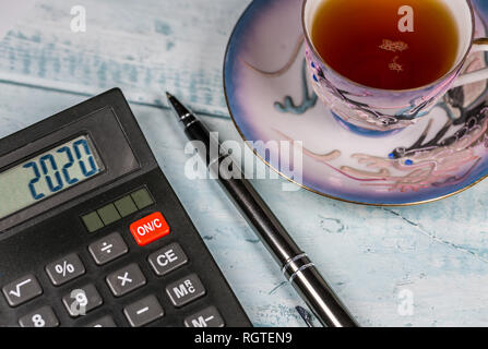 Tazza di tè, Calcolatrice e penna sulla scrivania in legno Foto Stock