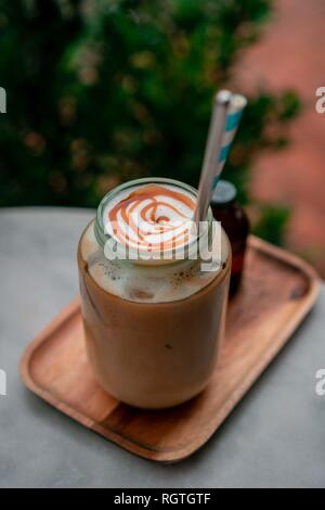 Vista dall'alto di fiori secchi decorare il piano portapaziente in cafe con glas di flat-caffè bianco sul vicino ad alcuni fiori. Foto Stock