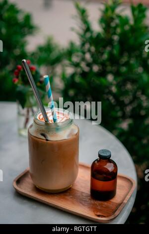 Vista dall'alto di fiori secchi decorare il piano portapaziente in cafe con glas di flat-caffè bianco sul vicino ad alcuni fiori. Foto Stock